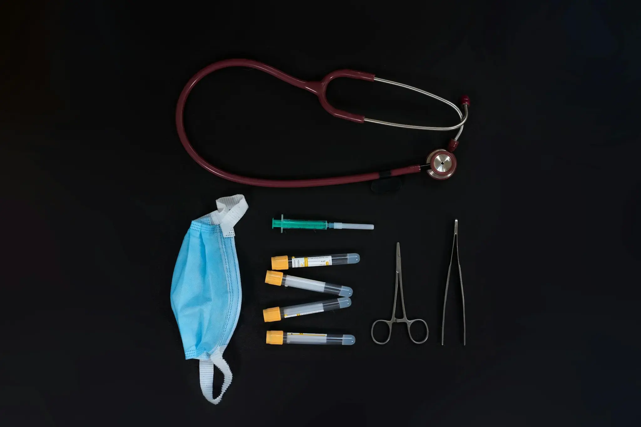 Kit de emergência com estetoscópio, seringa, tubos de coleta de sangue e instrumentos cirúrgicos sobre fundo preto