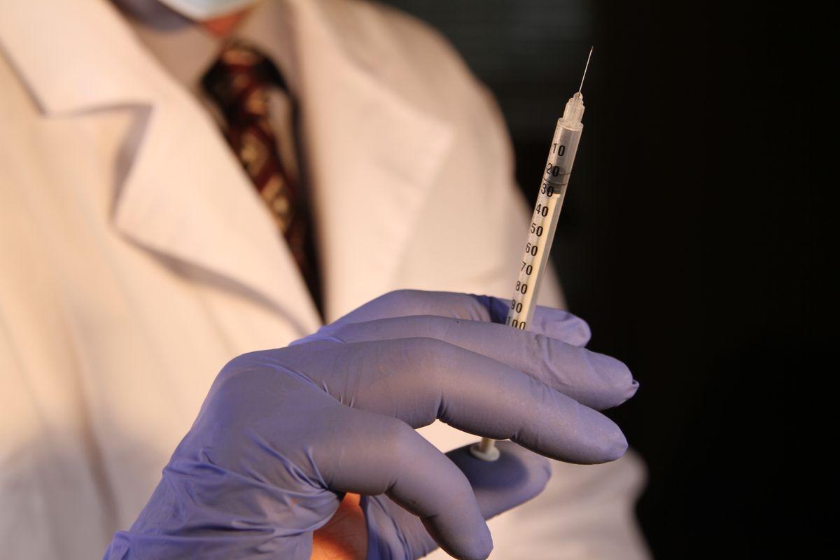 Profissional de saúde com luvas segurando seringa graduada preparada para administração intravenosa