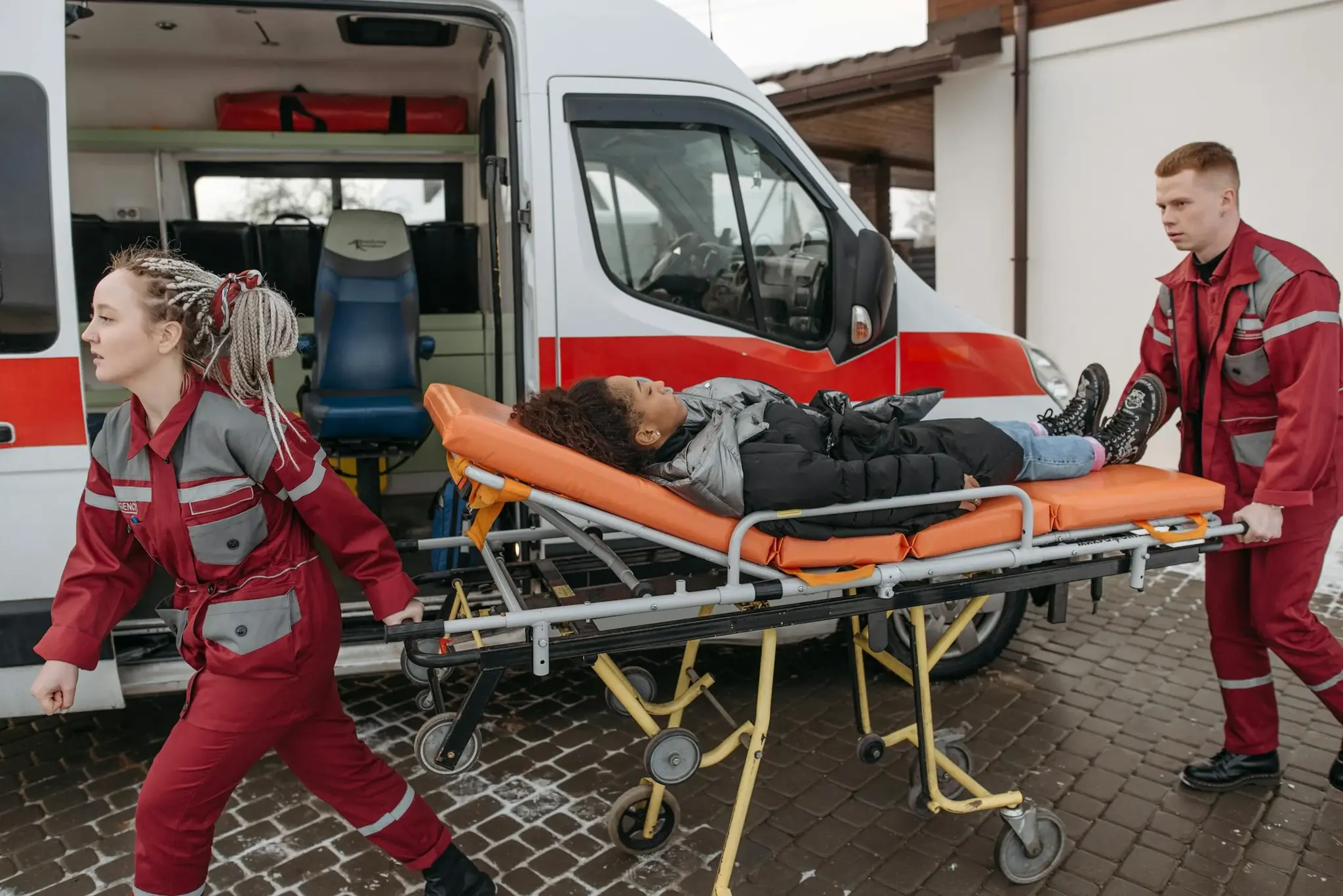 Equipe de paramédicos transportando paciente em maca de rodas para dentro de ambulância