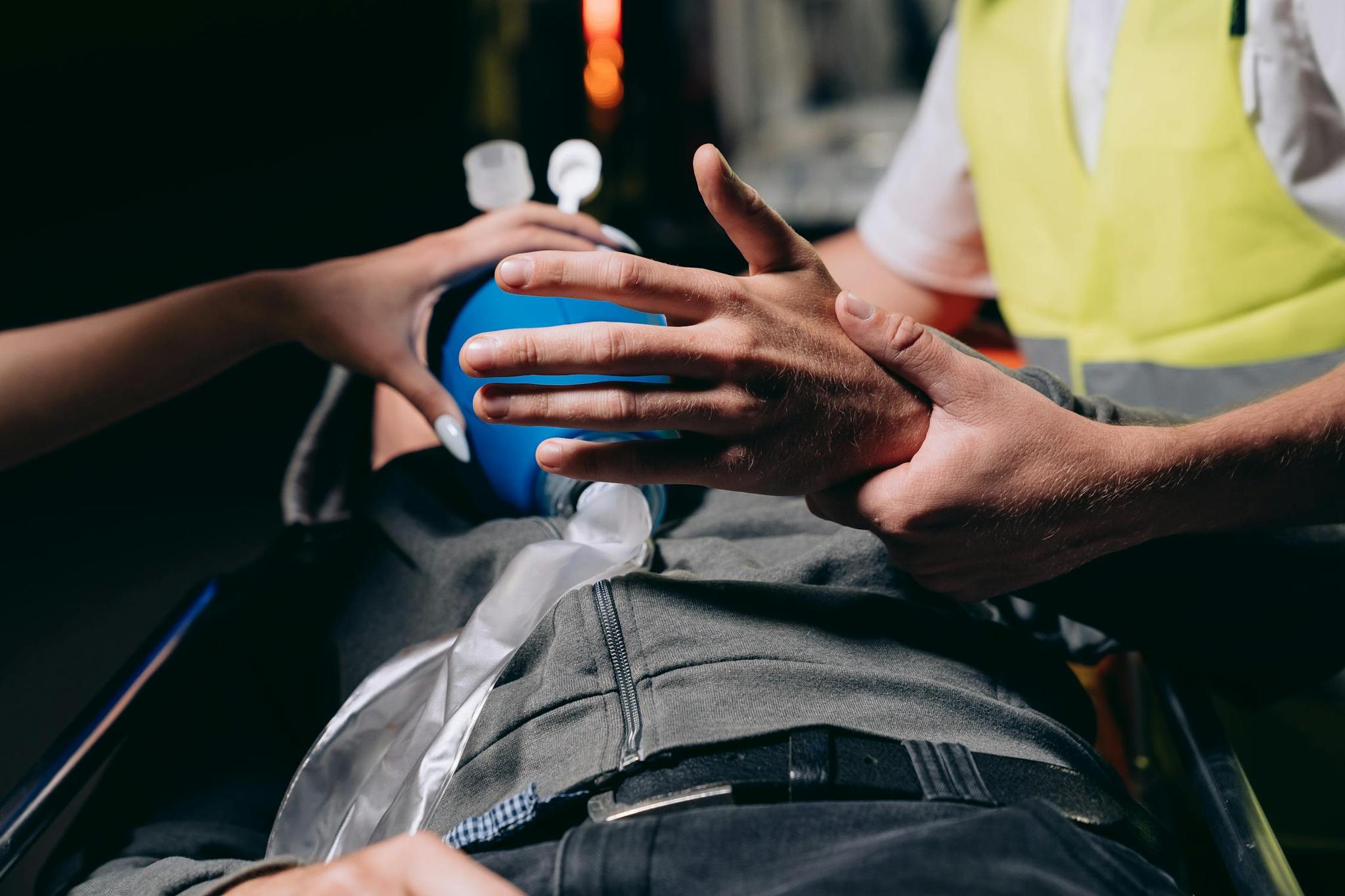 Socorrista ventilando paciente com bolsa-válvula-máscara (ambu) dentro de ambulância durante atendimento