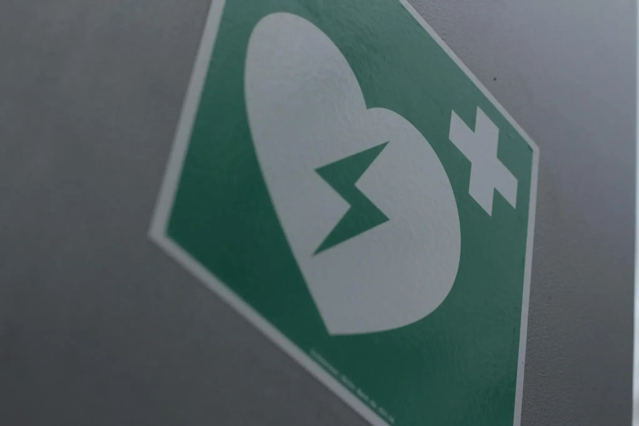 Placa de sinalização verde de desfibrilador (DEA) fixada em parede, close em ângulo