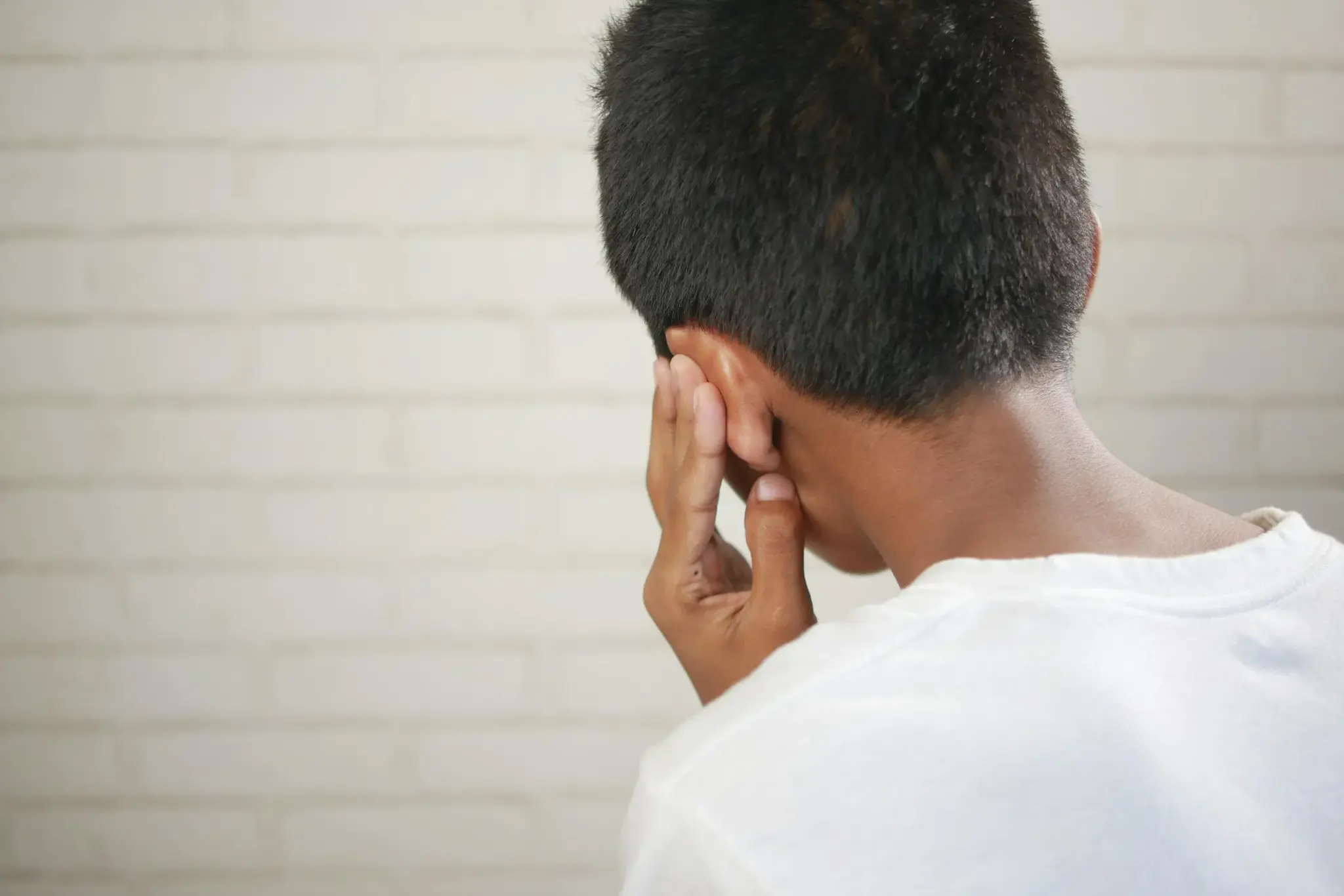 Criança de costas levando a mão à orelha, indicando dor ou desconforto auricular