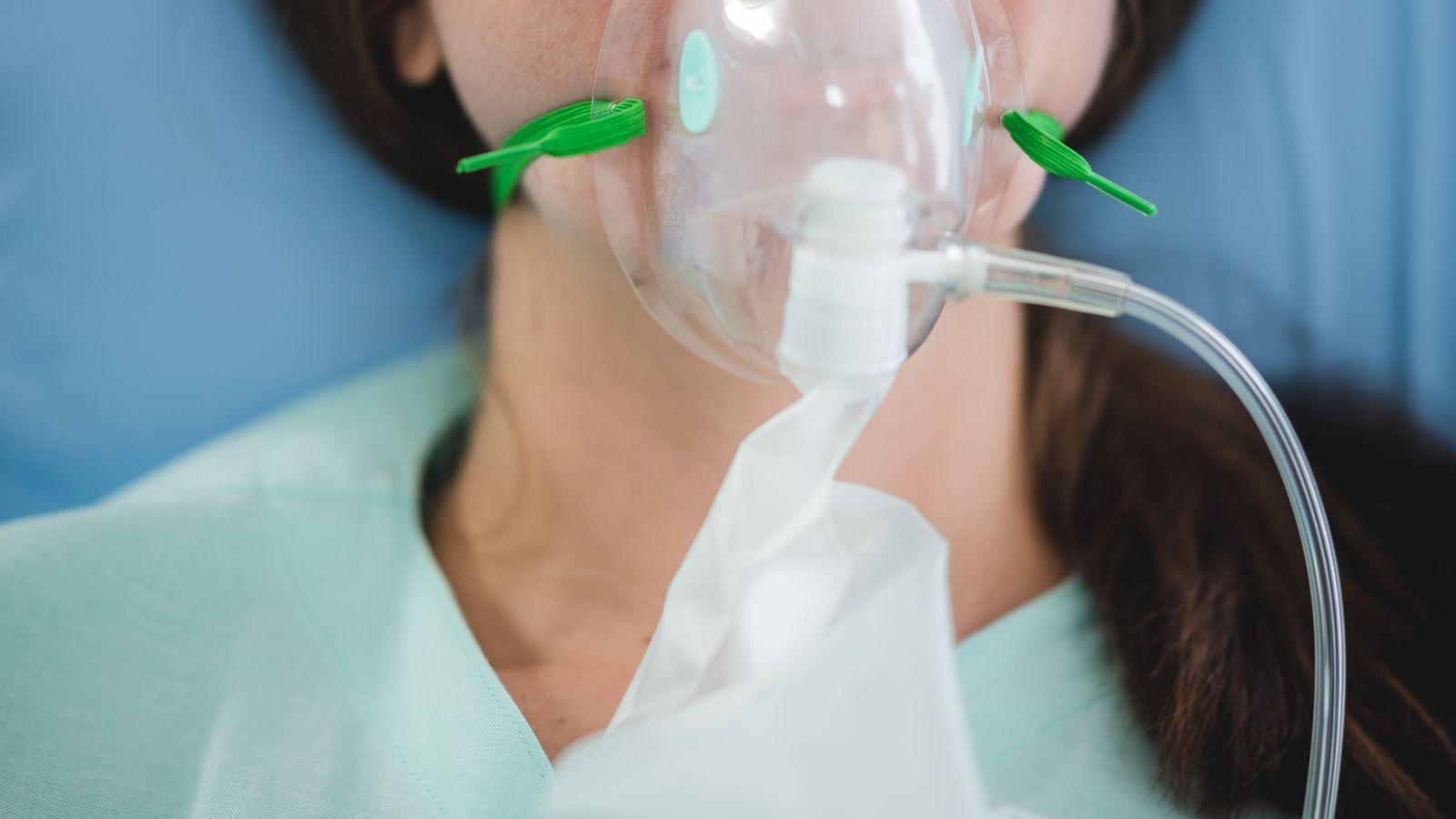 Máscara de nebulização acoplada a tubo corrugado em paciente, ilustrando o circuito de administração de gás umidificado
